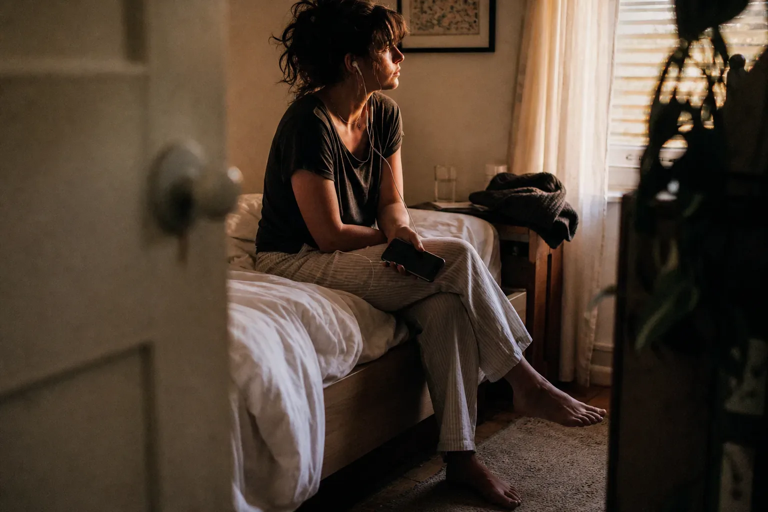 Person listening quietly beside an unmade bed