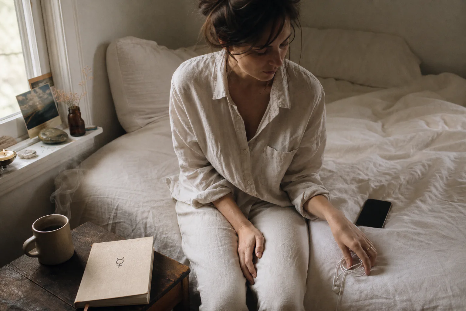 Woman listening to audio beside a bedside journal